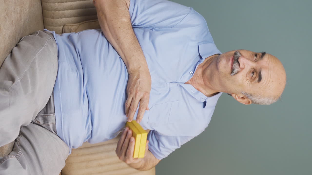 video vertical de un anciano esperando a alguien con una caja de regalos.