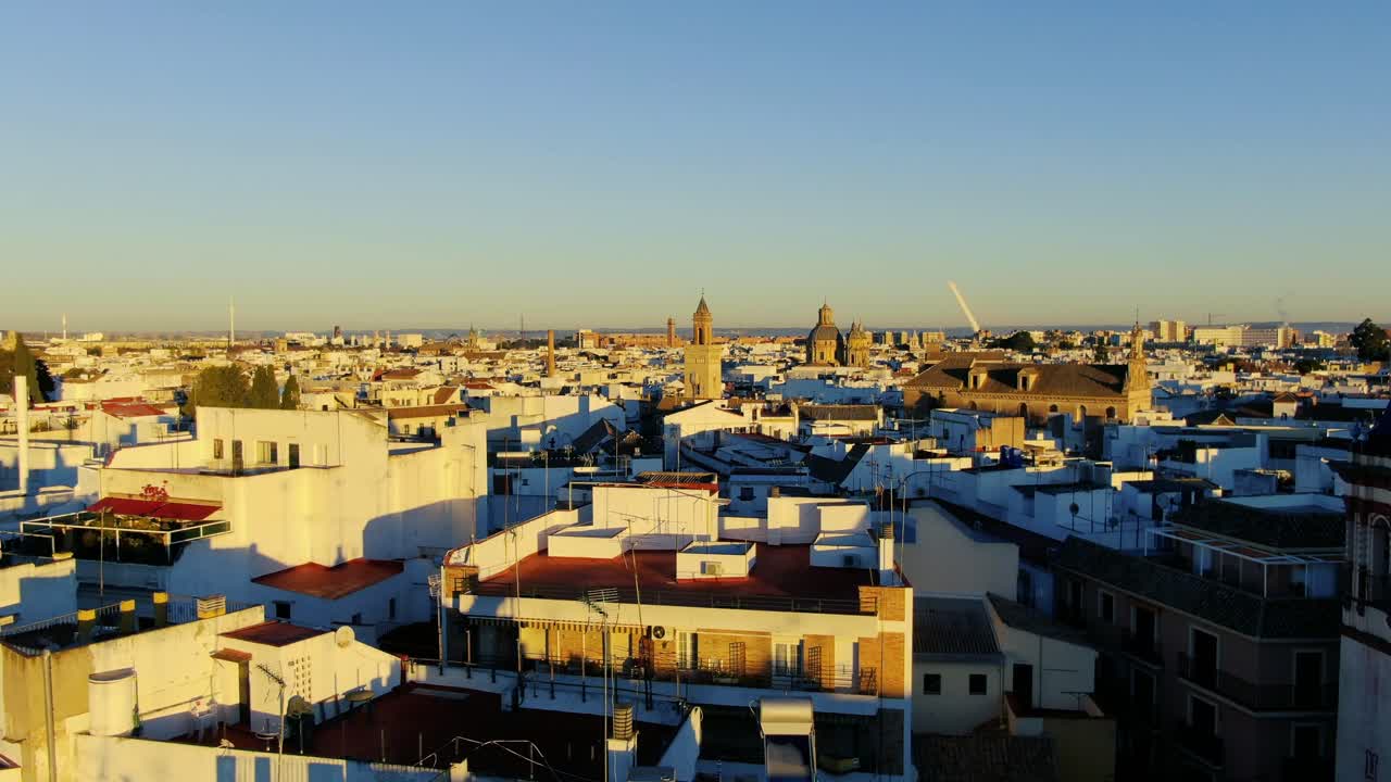 세비야의 역사적인 중심부에서 상승하는 공중 영상, 해가 지는 오렌지색으로 지붕과 교회를 볼 수 있습니다.