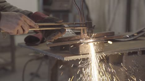 workplace hazard: metal worker cutting a thick steel plate with handheld plasma cutter