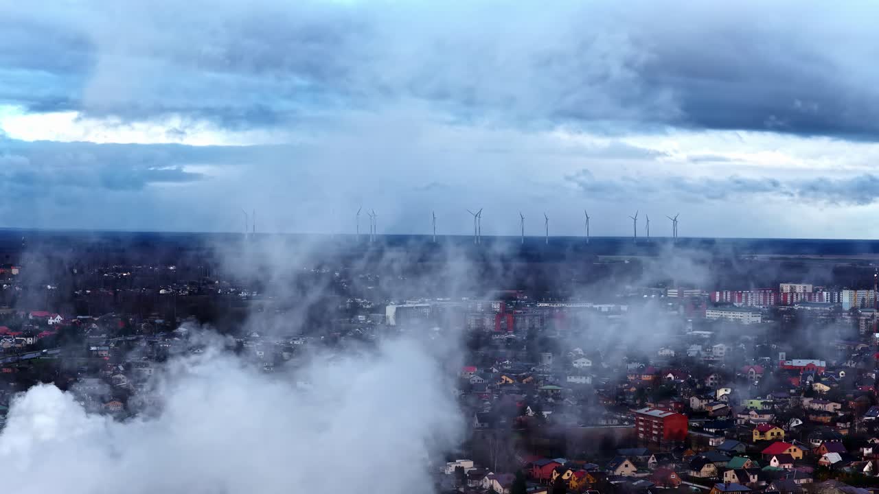 Vista aerea di un paesaggio urbano nuvoloso con turbine eoliche visibili in lontananza