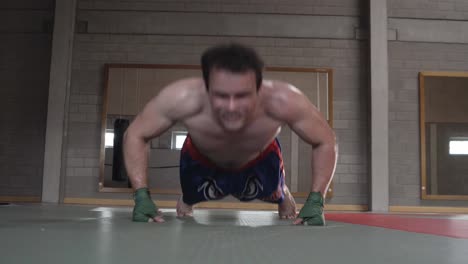 joven kickboxer haciendo flexiones rápidas en el gimnasio vacío