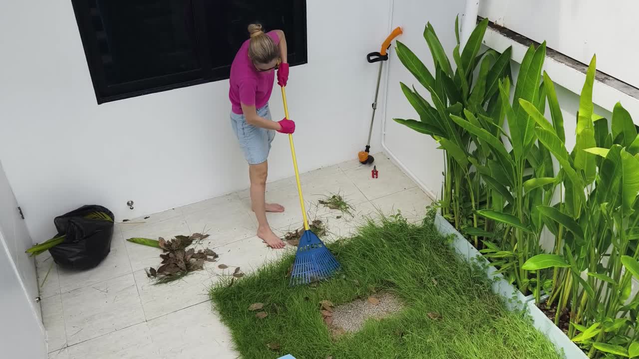 mujer rastrillando hojas en un jardín de patio