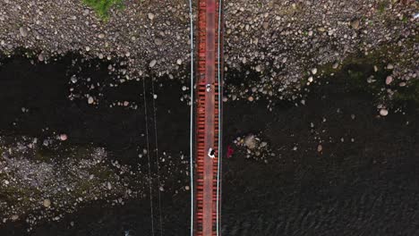 top down view of people crossing hanging footbridge in guinsaugon, southern leyte in the philippines - aerial drone shot