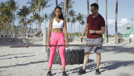 Man-supporting-girl-with-squats-on-beach