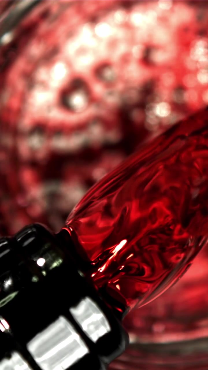 Liquido rosso vivace che si versa al rallentatore, primo piano