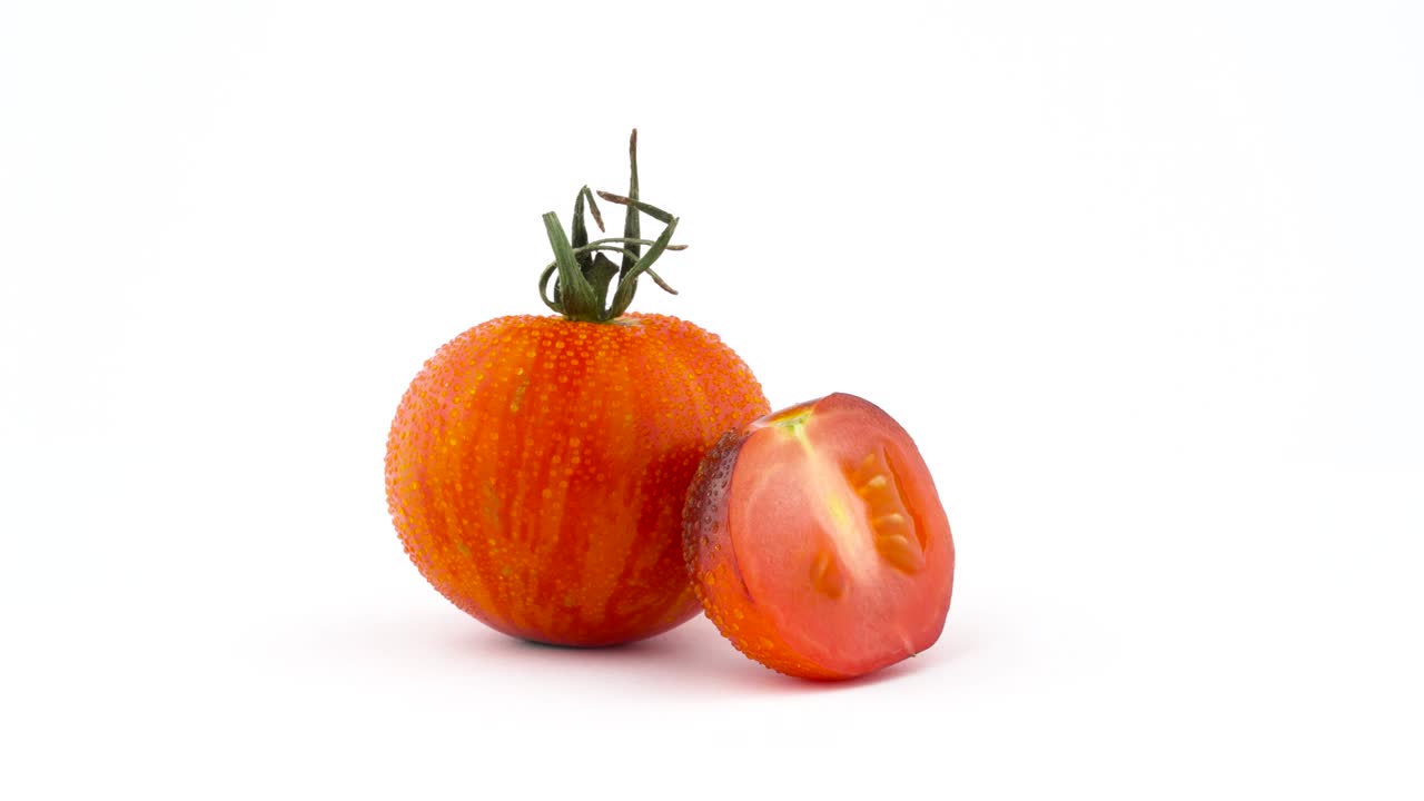 색 배경에 고립 된 회전 테이블에서 천천히 회전하는 은 지구 줄무 토마토와 인디고 로즈 토마토의 절반.