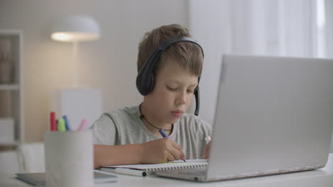 boy is drawing and watching cartoons by internet using laptop at home at vacation time green screen on notebook