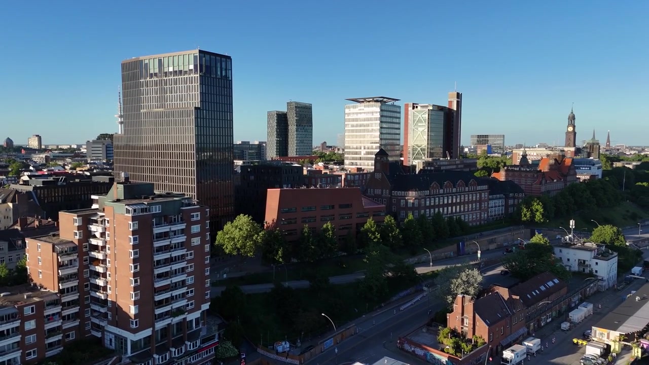 Drone nærmer sig fra siden mod Empire Riverside Hotel, der åbner den lagdelte Hamborgs bystruktur med tårne, kirker og Fernsehturm i parallax