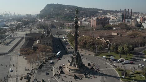 aerial: slow overhead flight over columbus monument in barcelona, spain with palm trees on beautiful sunny day [4k]