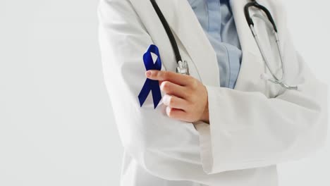 Video-of-midsection-of-caucasian-female-doctor-holding-blue-colon-cancer-ribbon,-with-copy-space