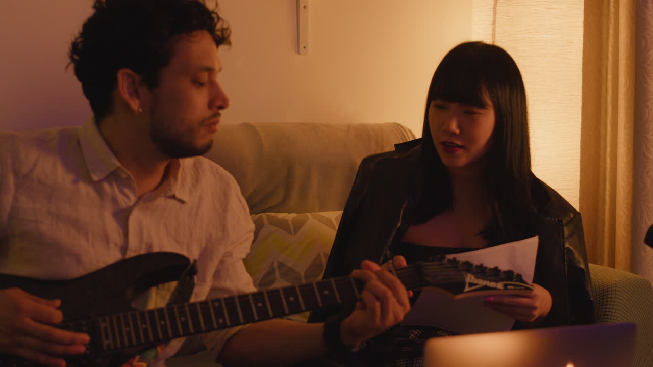 Couple playing guitars by candlelight