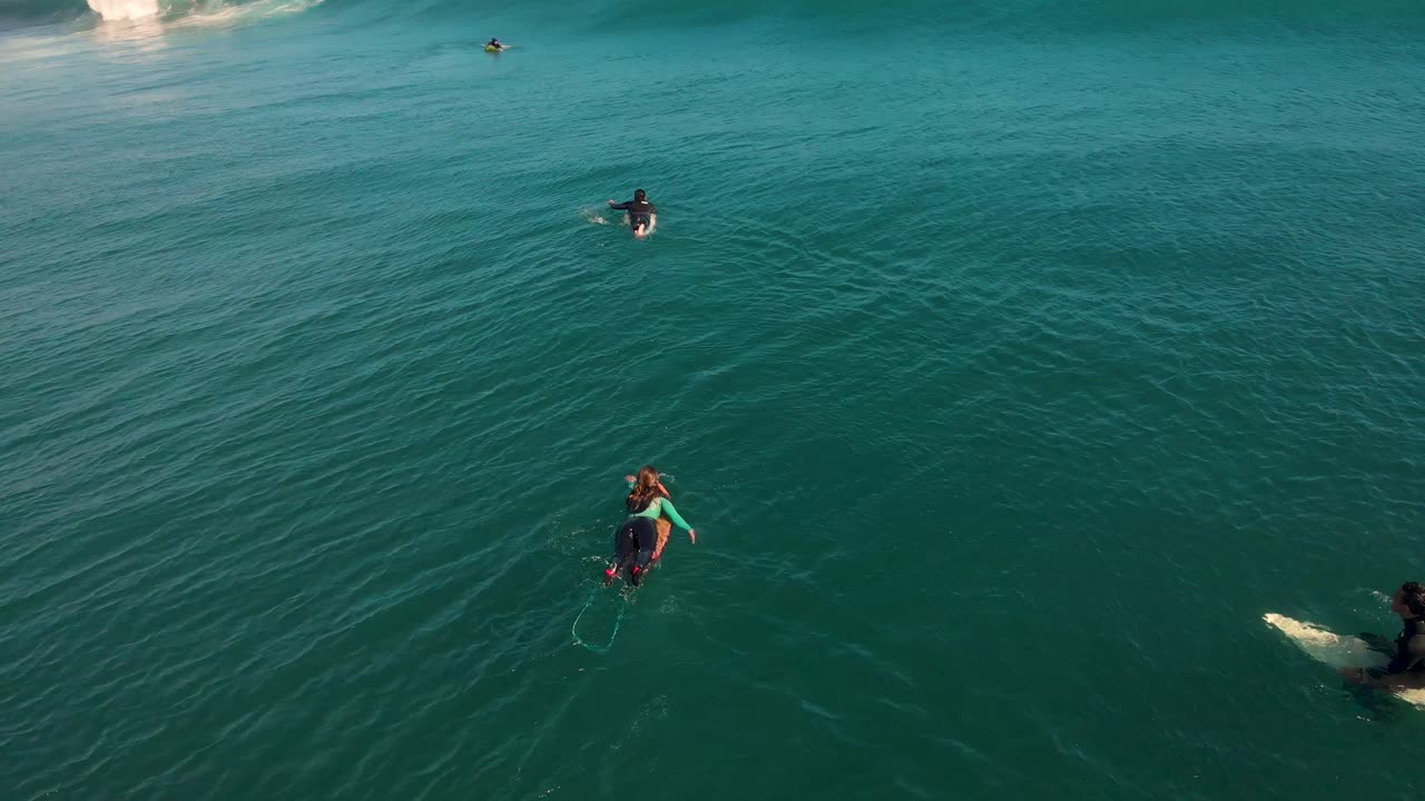 Girl paddling on turquoise water crossing a wave next to other surfers, Pichilemu, Chile-4K