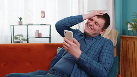 슬프고 불만스러운 남자 스마트폰 브라우징을 사용하여 놀란 게임 결과를 잃습니다. 나쁜 소식은 앱 바이러스가 실패합니다.