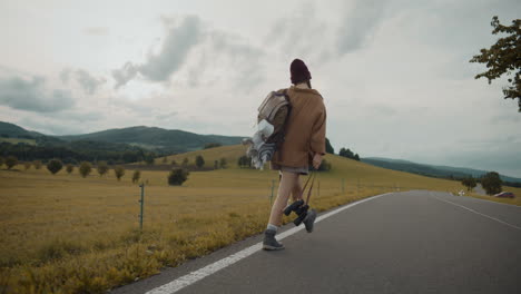 Explorer-with-backpack-and-binoculars-walking-on-road