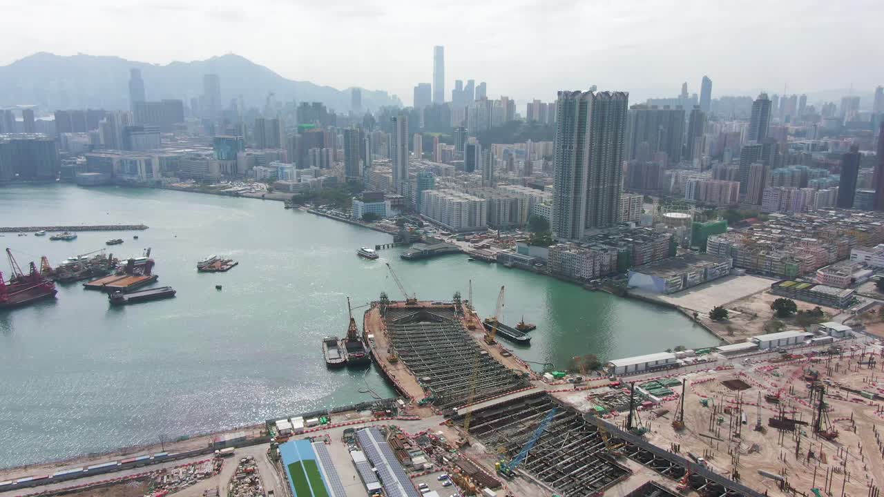Converting an old runway strip into a Housing and business district at Kai Tak downtown Hong Kong, with vast infrastructure development land and an underwater tunnel laying operation, Aerial view.
