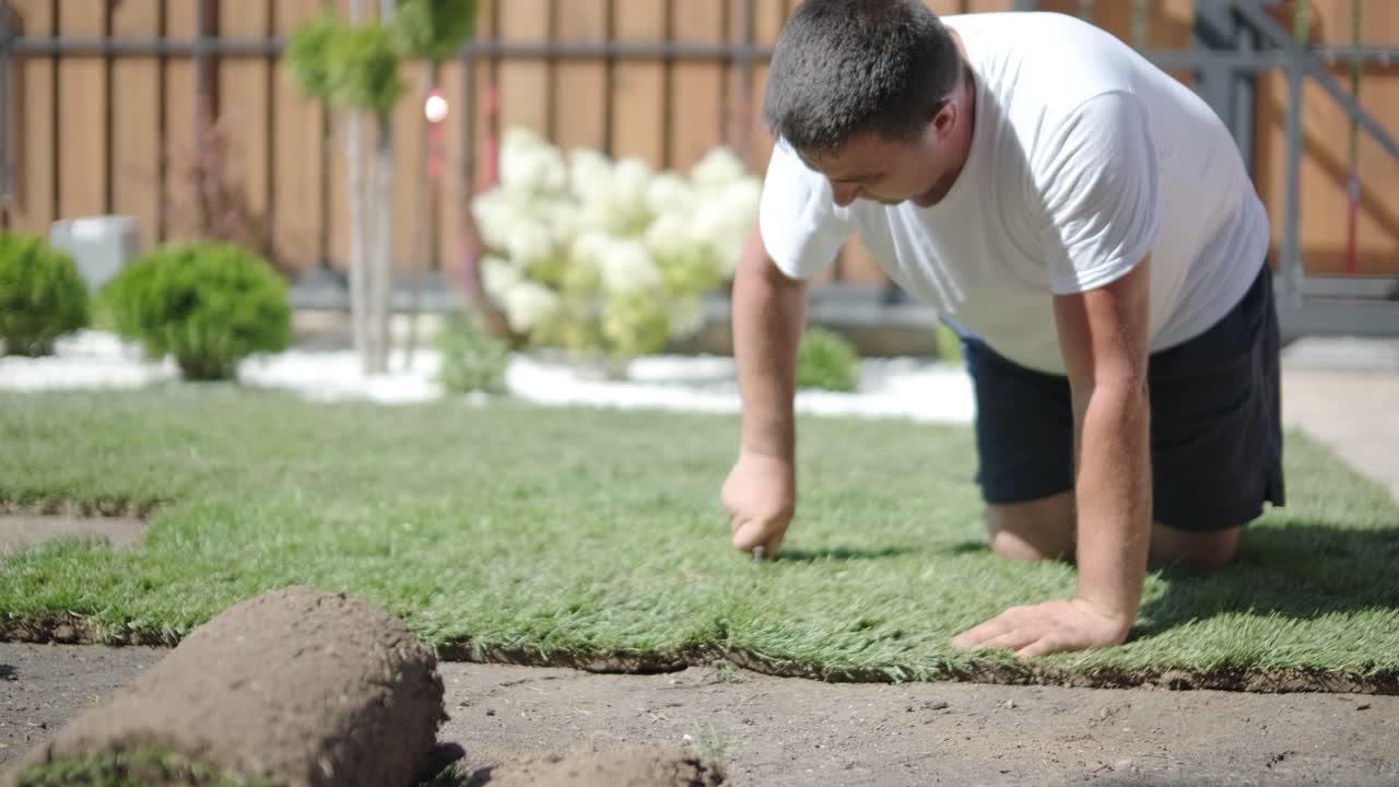 hombre colocando césped en el jardín del patio trasero para la instalación de césped y proyecto de jardinería, centrado en la mejora del hogar y el mantenimiento al aire libre para un césped fresco y verde en un patio residencial