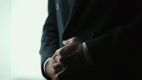 confident businessman buttoning or adjust classic blue suit near window in hotel room at the morning. handsome man wearing a nice suit on wedding day.