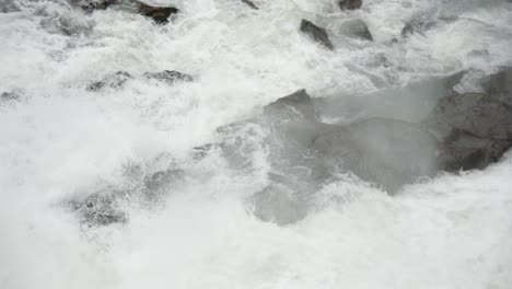 close tracking shot of majestic waterfalls careening over river rocks forming white water rapids