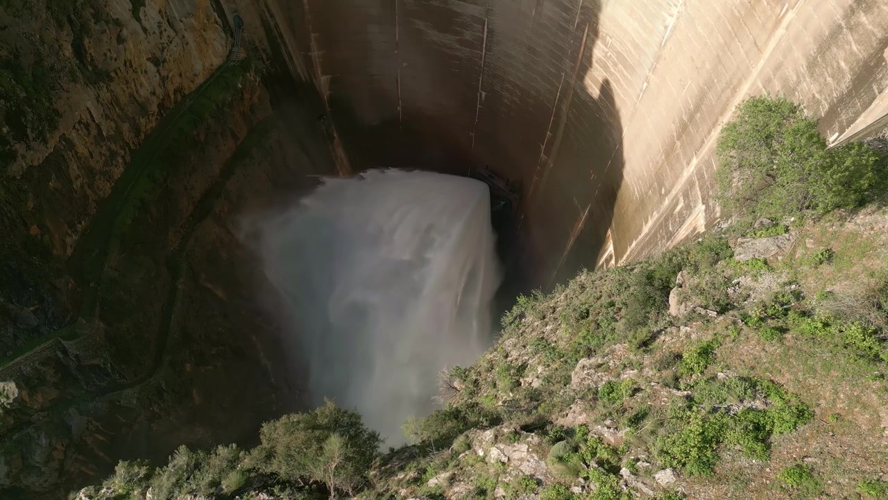 Acqua di scarico della diga. Vista aerea dall'alto dell'uscita dell'acqua dalla diga. Valvola Howell Bunger in funzione in una diga a volta. Bacino di Quentar. Spagna.
