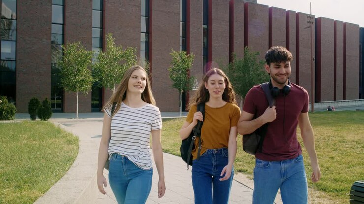Tre studenti caucasici che camminano nel campus universitario.