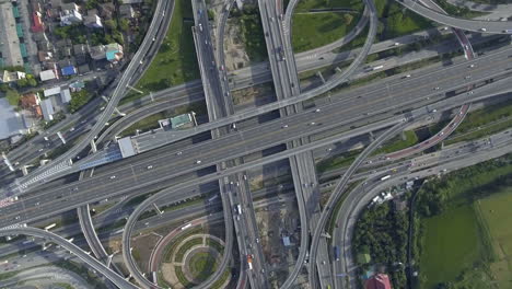 Vista-Aérea-Del-Cruce-De-Carreteras-Con-Tráfico-Urbano-Intenso-Acelerando-En-La-Carretera