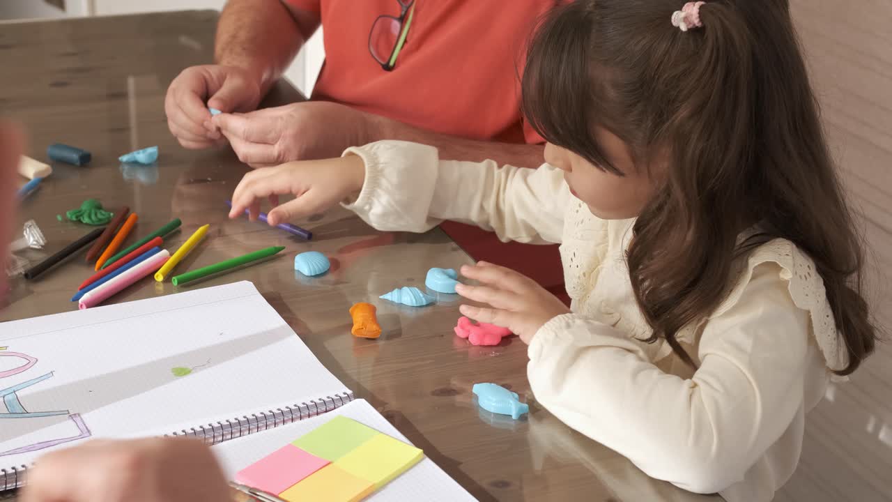 Girl playing with plasticine next to her grandfathers