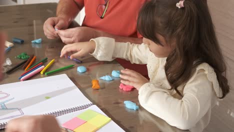 girl playing with plasticine next to her grandfathers