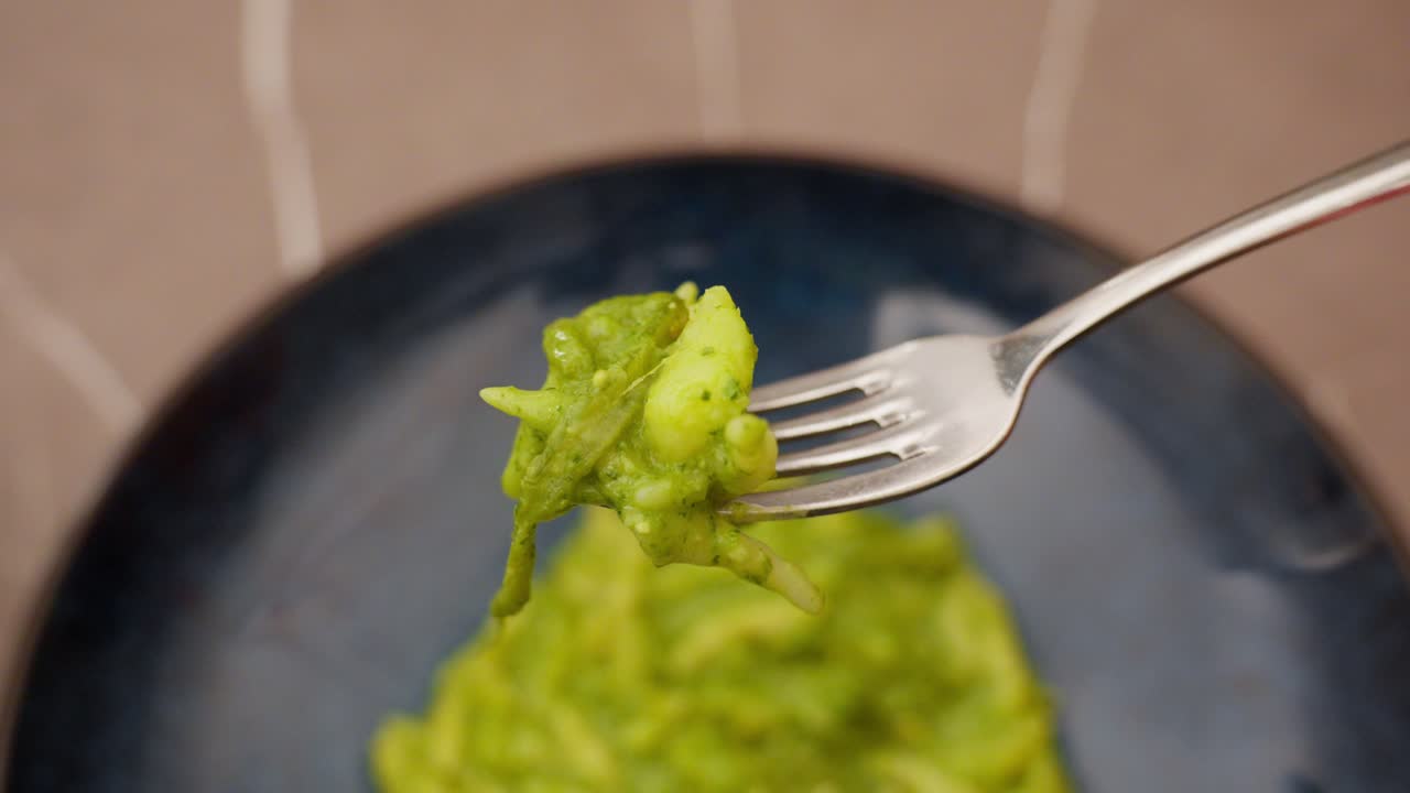Close-up of fork with green pesto pasta, typical Genoa delicacy made with basil