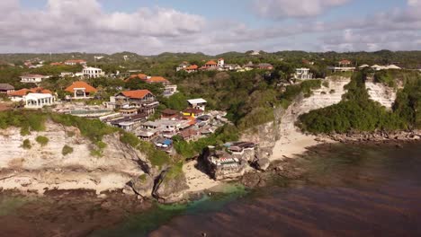 drone shot of suluban beach on bali indonesia with visible rocks bars and hotels on a cliff in afternoon sun in the summer during low tide