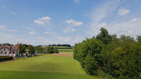 Landschaft-Mit-Grünen-Feldern,-Blauem-Himmel-Und-Wohnhäusern-An-Einem-Schönen-Sonnigen-Tag-In-Norditalien---Drohnenaufnahme-Aus-Der-Luft