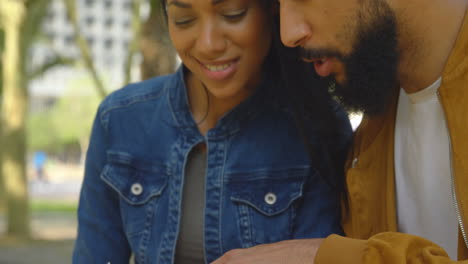 joven pareja de raza mixta feliz discutiendo por teléfono móvil en la ciudad 4k
