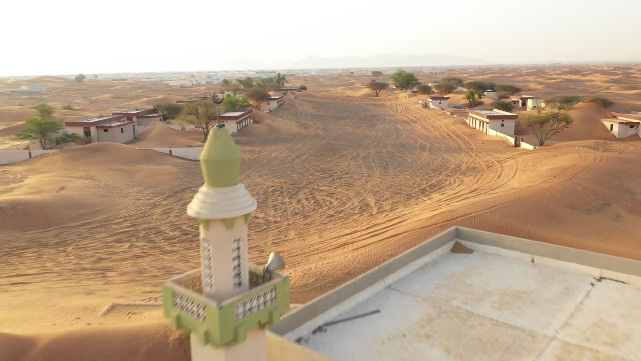 vista aérea de un pueblo abandonado vacío y casas con una mezquita cubierta de arena del desierto cerca de dubai