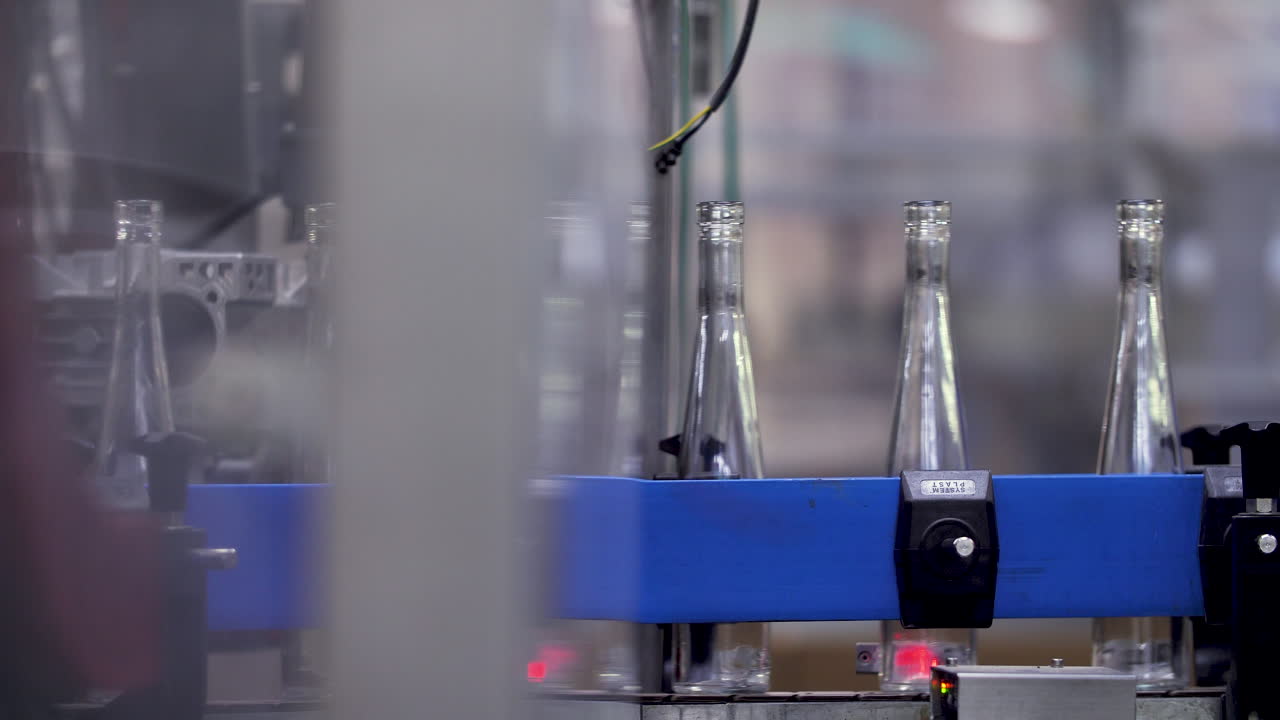 Empty slender wine bottles carried by an automated conveyor belt from one part to another of a winery