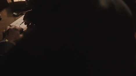 old passionate man writes a letter in his office at night