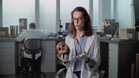 archaeologist presenting a human skull in a laboratory setting