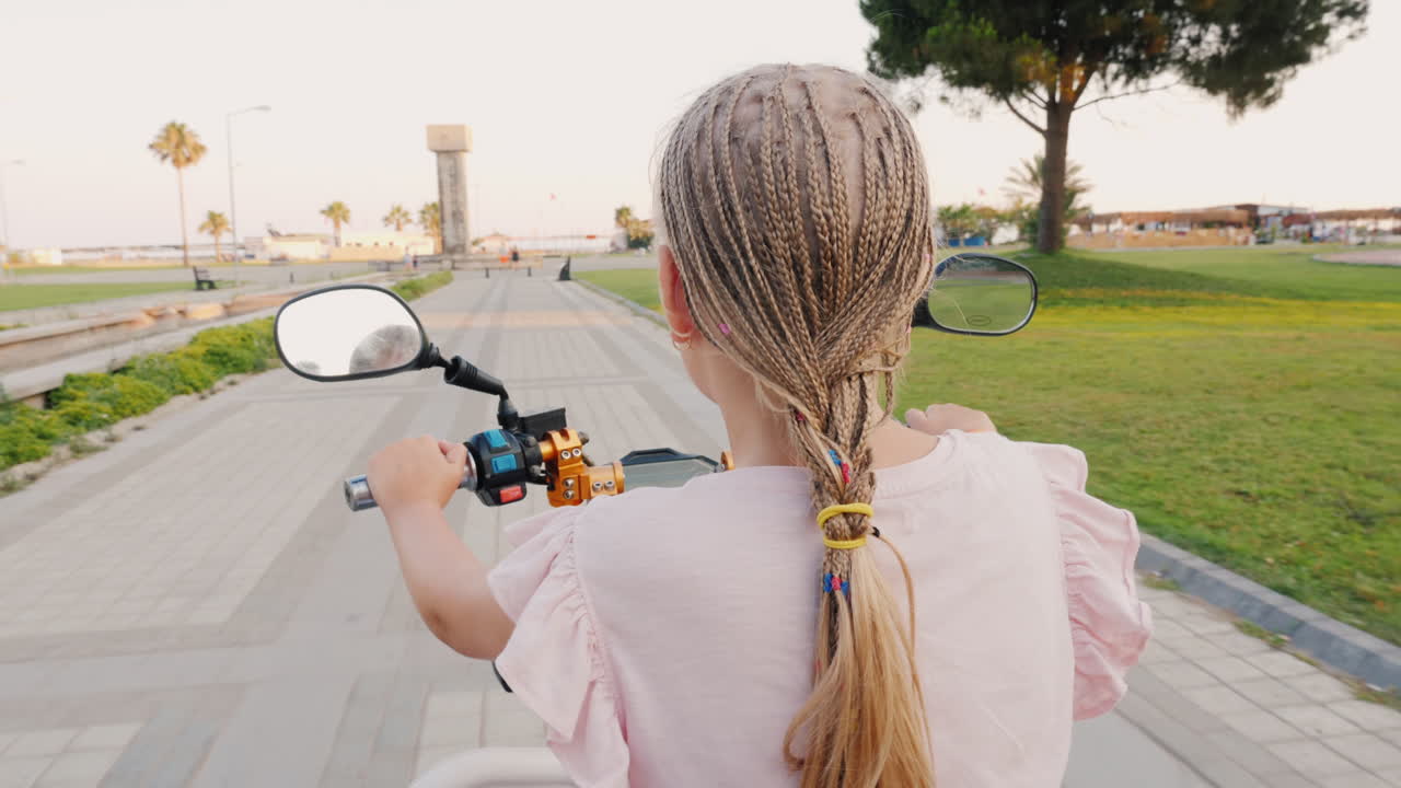 스쿠터 뒷모습을 타고 있는 아프리카 땋은 머리를 가진 아이는 명랑하고 활동적인 레크리에이션