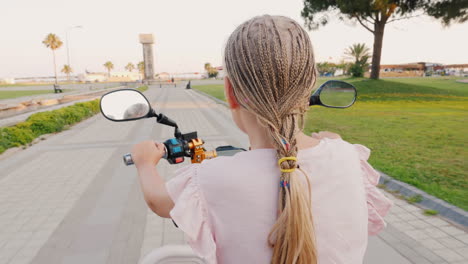 A-Child-With-African-Pigtails-Riding-A-Scooter-Rear-View-Cheerful-And-Active-Recreation