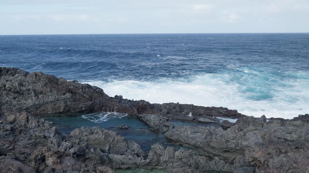 Onde oceaniche che si infrangono sulla costa rocciosa con piscine naturali