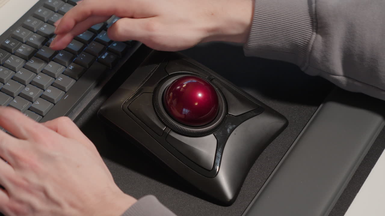Man using Trackball as a mouse and typing on keyboard
