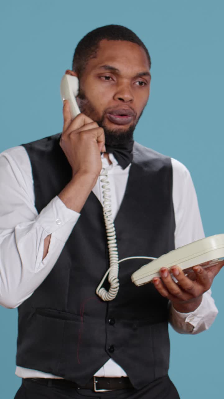Cameriere professionista che parla al telefono fisso vintage