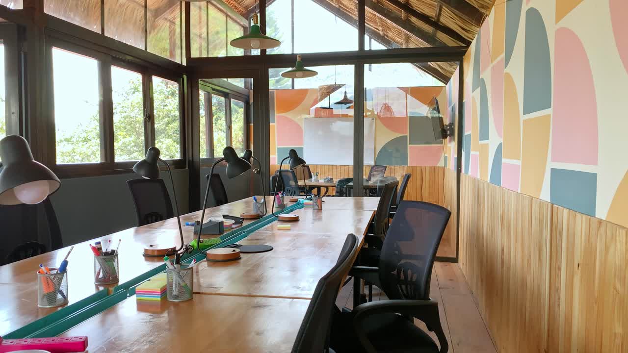 Empty Hostel Shared Workspace Facility With Wooden Long Conference Table And Black Office Chairs