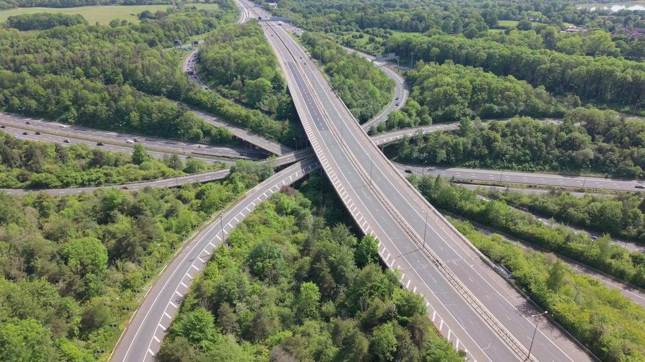 An aerial perspective shows a vast highway interchange with cars and trucks traveling on multiple lanes.