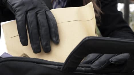 business woman putting documents and envelopes in briefcase close up shot