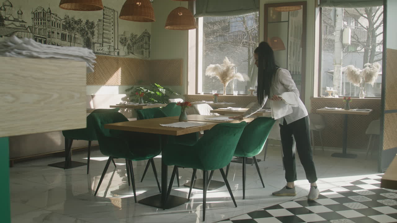 Restaurant interior with waitress setting tables