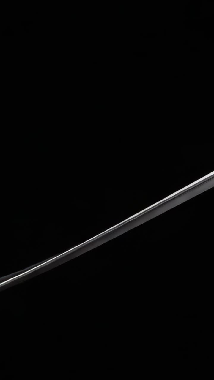 Vertical video: Emerging metallic-silver arc gliding diagonally across black void, sweeping upward