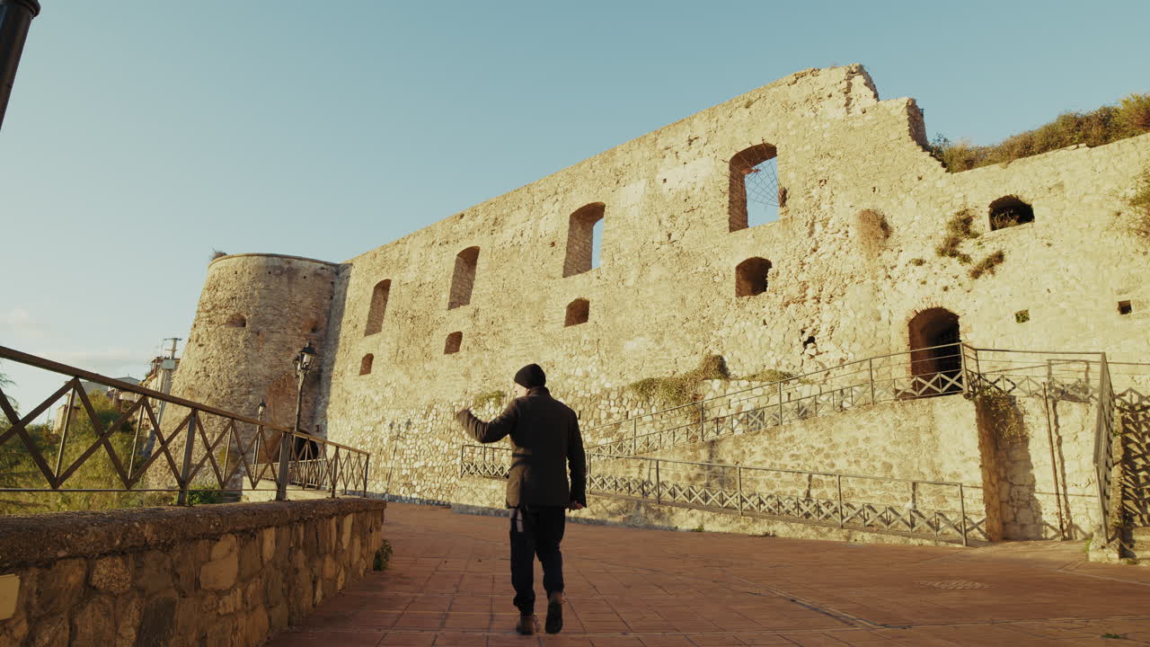 турист-мужчина исследует средневековый замок в деревне итальянского города