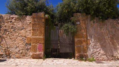 old stone wall with gate in sunny scopello city center, sicilia, italy