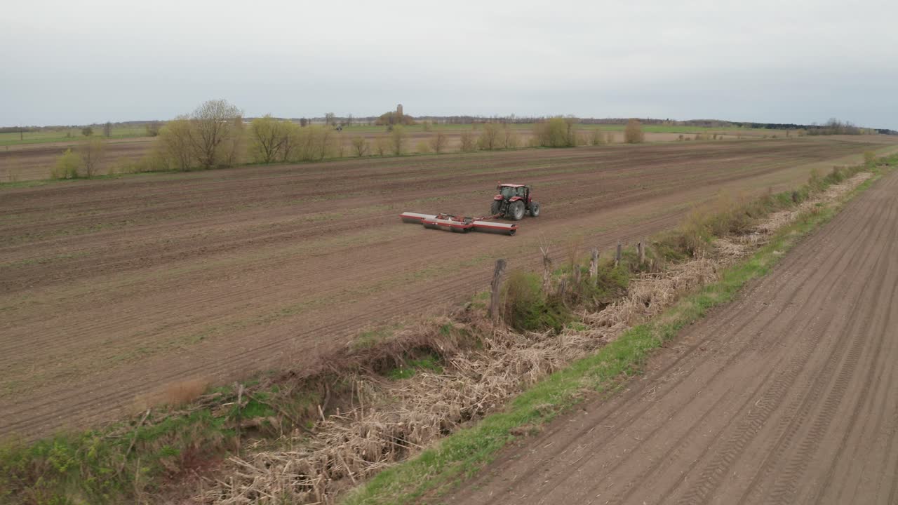 vista aérea desde un dron que sigue al tractor mientras ara campos agrícolas fértiles para prepararse para la siembra