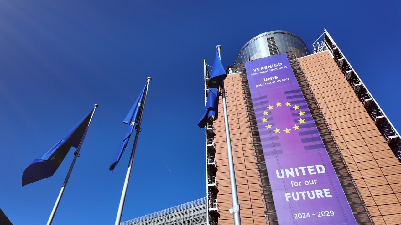 EU flags waving in front of European Commission building with banner