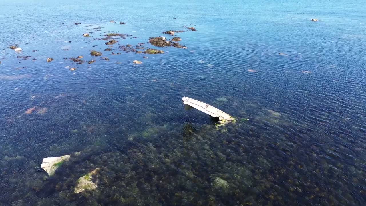 Parts of a metal ship wreck poking out of calm shallow sea